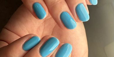 Close-up of hands with glossy blue gel nails.
