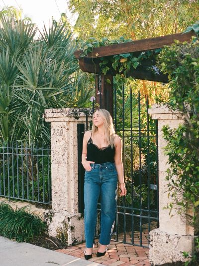 Young woman standing by a garden gate.