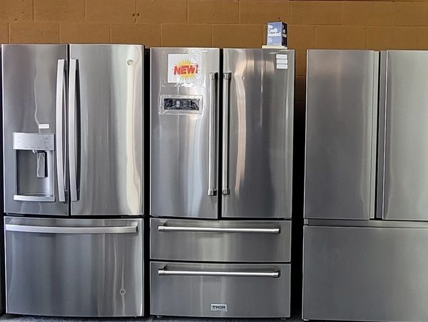A row of three used stainless steel refrigerators.