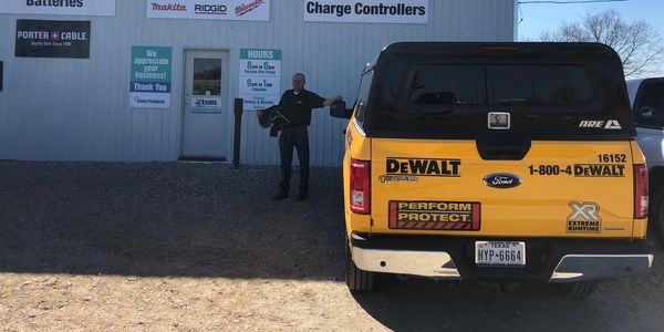 Man standing by a Dewalt company truck in front of the Ennis Products store.