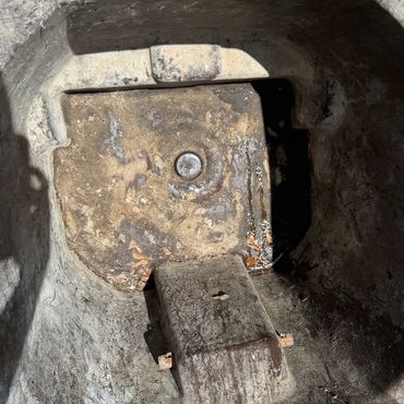 Dirty, empty trash bin on concrete ground with a shadow.