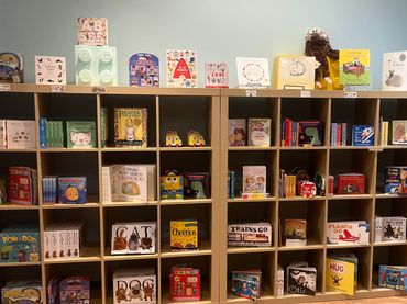 Children's books neatly arranged on wooden shelves in a cozy reading corner.