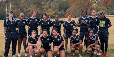 A team of female athletes posing for a group photo outdoors.