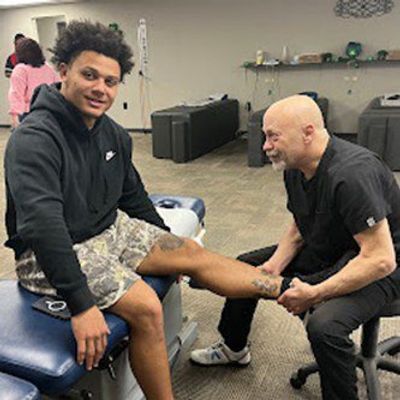A healthcare professional assesses a patient's leg in a therapy room, focusing on rehabilitation.