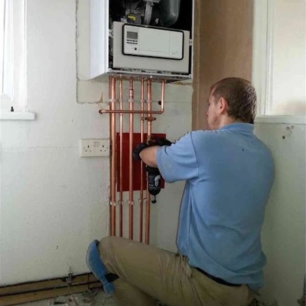 a man repairing the plumbing for a boiler