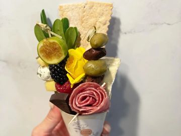 Hand holding a charcutie cone filled with food