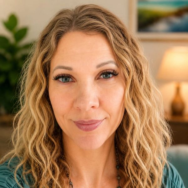 Close-up portrait of a woman with curly blonde hair and blue eyes.