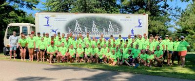 Large group in neon green shirts posing outdoors in front of a truck.