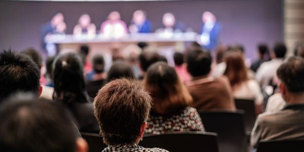 Audience attentively listening to a panel discussion at a conference.