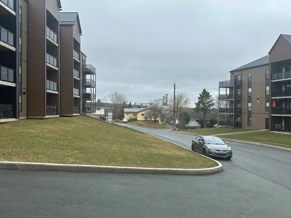 A lone car parked on a street between apartment buildings on a cloudy day.