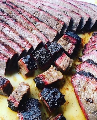 Sliced smoked brisket with a charred bark and pink smoke ring.