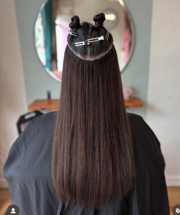 Long, straight hair sectioned and clipped with hairpins in a salon setting.