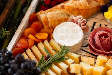 Charcuterie board close up - Brie cheese, manchego cheese, dried apricots, salami rose, fruits