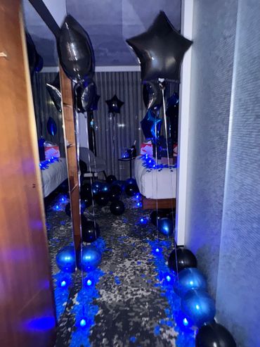 black and blue balloons leading to a bed in a decorated hotel room in boston