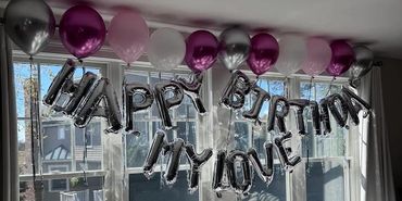 happy birhday balloons hanging from the window of a decorated hotel room in boston