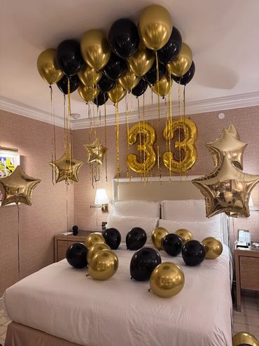 black and gold balloons on a bed with numbered balloons for a birthday in boston hotel room