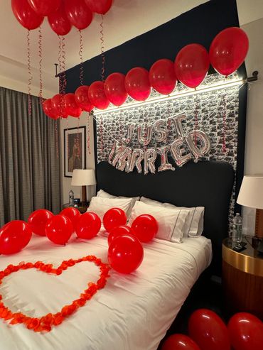 red balloons on a bed with rose pedals in a decorated hotel room in boston