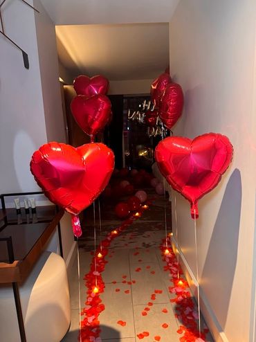 heart balloons and rose pedals lining a hallway in a decorated hotel room in boston