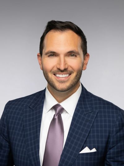 Smiling man in checkered navy suit and purple tie.
