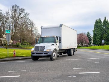 Small compact semi truck with cube box trailer transporting commercial cargo