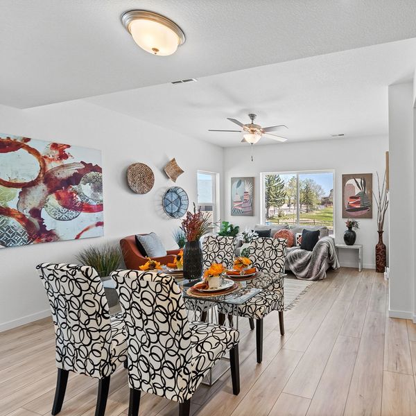 Modern dining and living area with patterned chairs and bright decor.