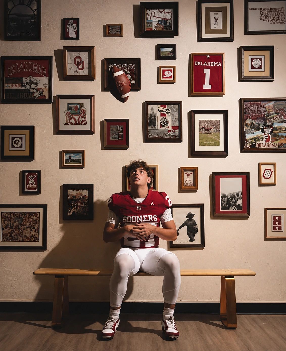 Football player sitting on a bench under sports memorabilia.