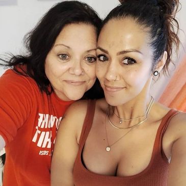 Two women smiling closely together for a selfie, showing a warm bond.