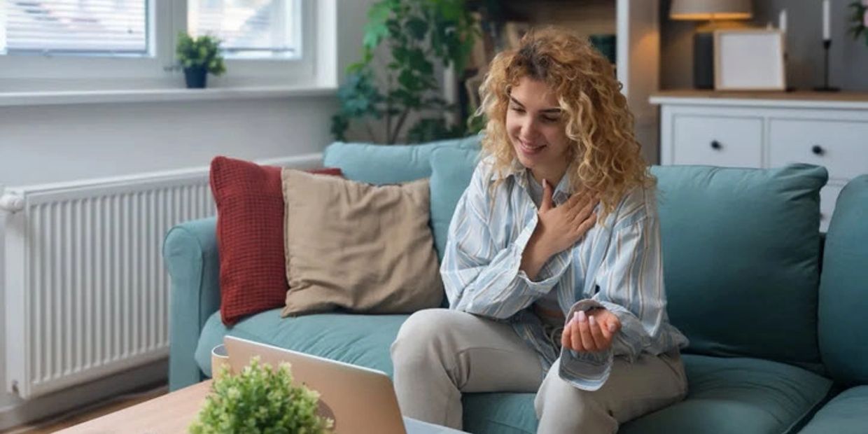 A woman smiling and talking on a video call at home.
