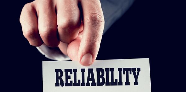 A hand holding a sign that reads reliability counts