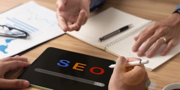 A person using a tablet with the words SEO displayed on the screen.