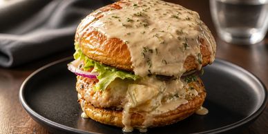 Juicy chicken burger with creamy sauce on a rustic bun.
