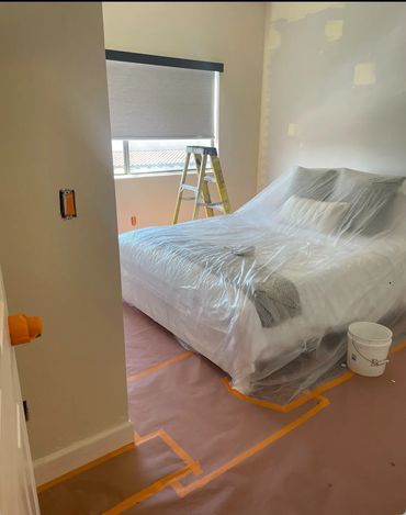 Bedroom prepared for painting with protective coverings on furniture and floors