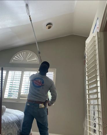 Professional painter applying white paint to bedroom ceiling in Yorba Linda home