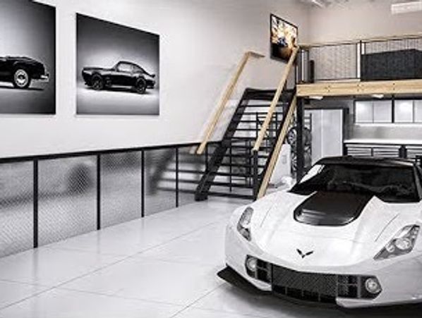 White sports car in a modern garage with car photos on the wall.