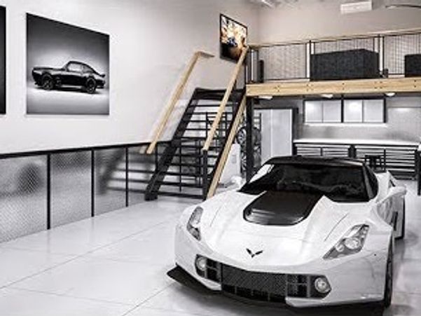 White sports car in a modern garage with car photos on the wall.