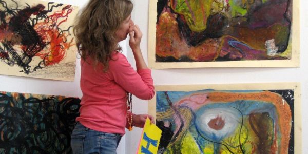 Woman observing colorful abstract paintings in a gallery.