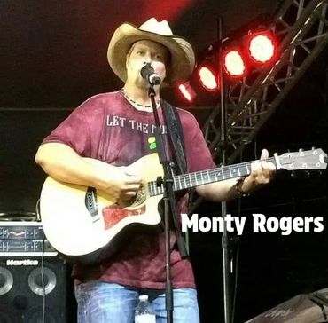 Monty Rogers performing on stage with a guitar and cowboy hat.