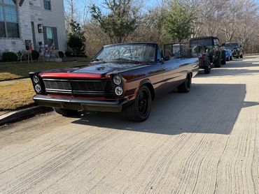 Classic convertible car parked on a sunny suburban street.