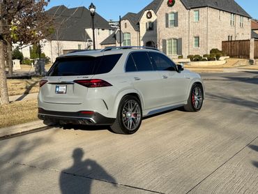 Gray Mercedes-Benz GLE 53 AMG parked on a suburban street with houses in the background.
