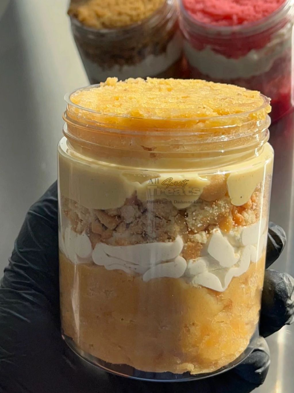 A layered dessert in a jar with creamy and crumbly textures.