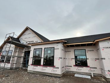 A house under construction with scaffolding and protective wrap.