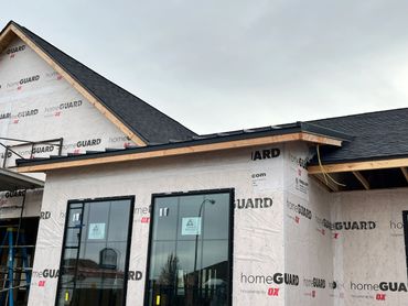 New house under construction with HomeGuard housewrap and black roofing.