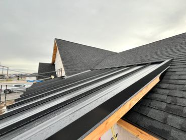 Newly installed black metal roofing on a residential building under construction.