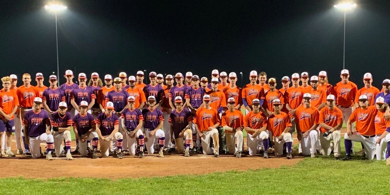 A large baseball team posing together on the field at night.