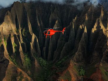 red helicopter with fluted mountains behind