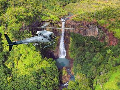 helicopter flying toward waterfall