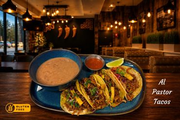 Al Pastor tacos served with beans and salsa in a cozy, warmly lit restaurant.
