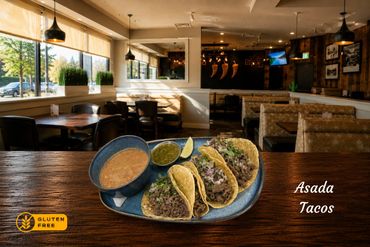 Plate of gluten-free asada tacos with sauces in a cozy restaurant.