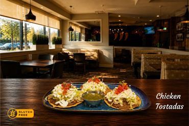 Gluten-free chicken tostadas with charro beans, fresh cheese, sour cream, tomatoes, onionand your side of salsa verde or roja.