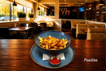 A bowl of poutine with fries, cheese curds, and gravy on a wooden table in a cozy restaurant.